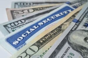 Several U.S. dollar bills fanned out, showing denominations like $50 and $100 in a close-up composition.